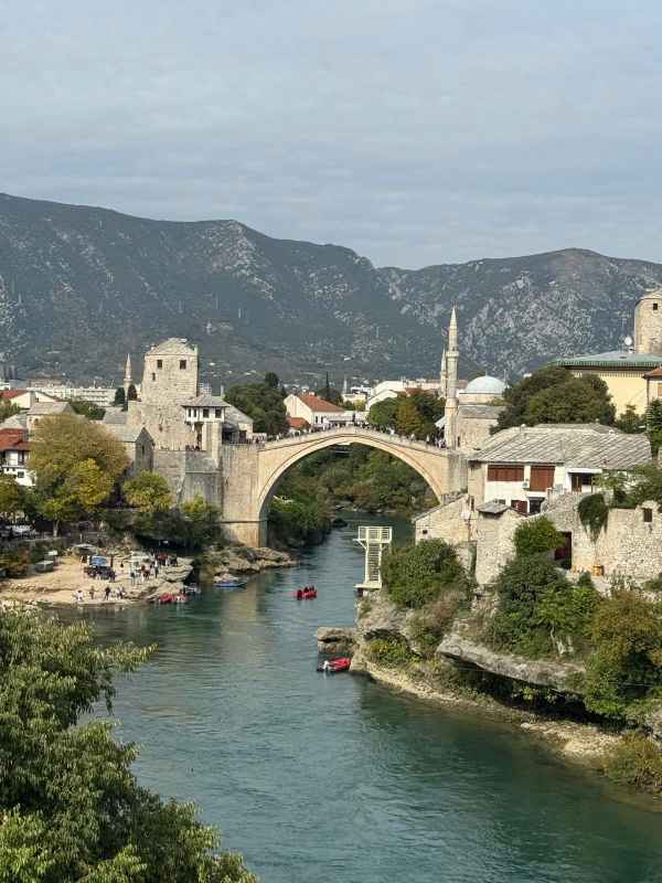 Mostar y su Puente Viejo sobre el río Neretva Puente Viejo de Mostar, de piedra y con un gran arco, sobre el río Neretva, rodeado de casas tradicionales, minaretes y montañas.