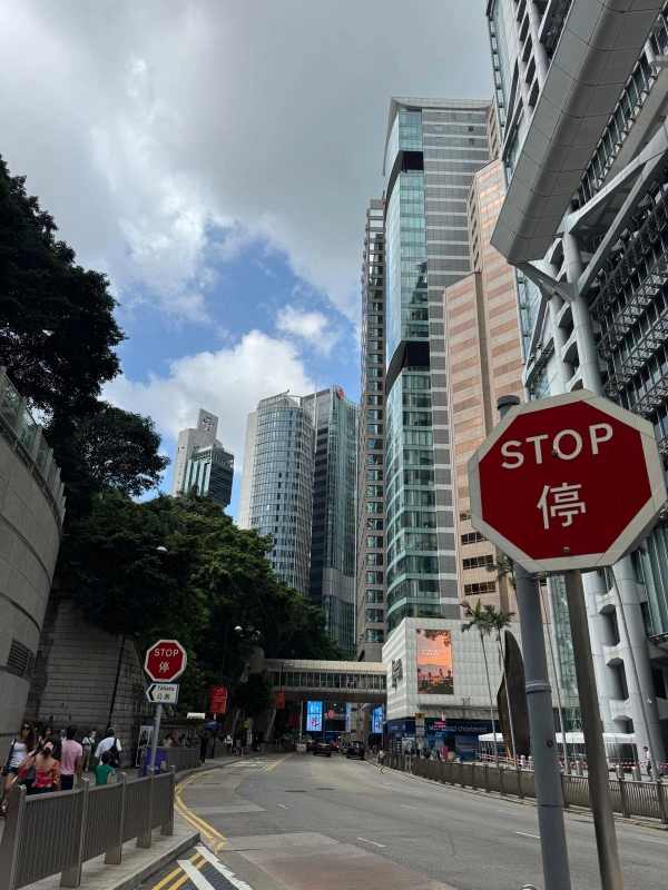 Calle del distrito de Central, en Hong Kong, rodeada de rascacielos, con una señal roja de STOP en inglés y chino en primer plano.